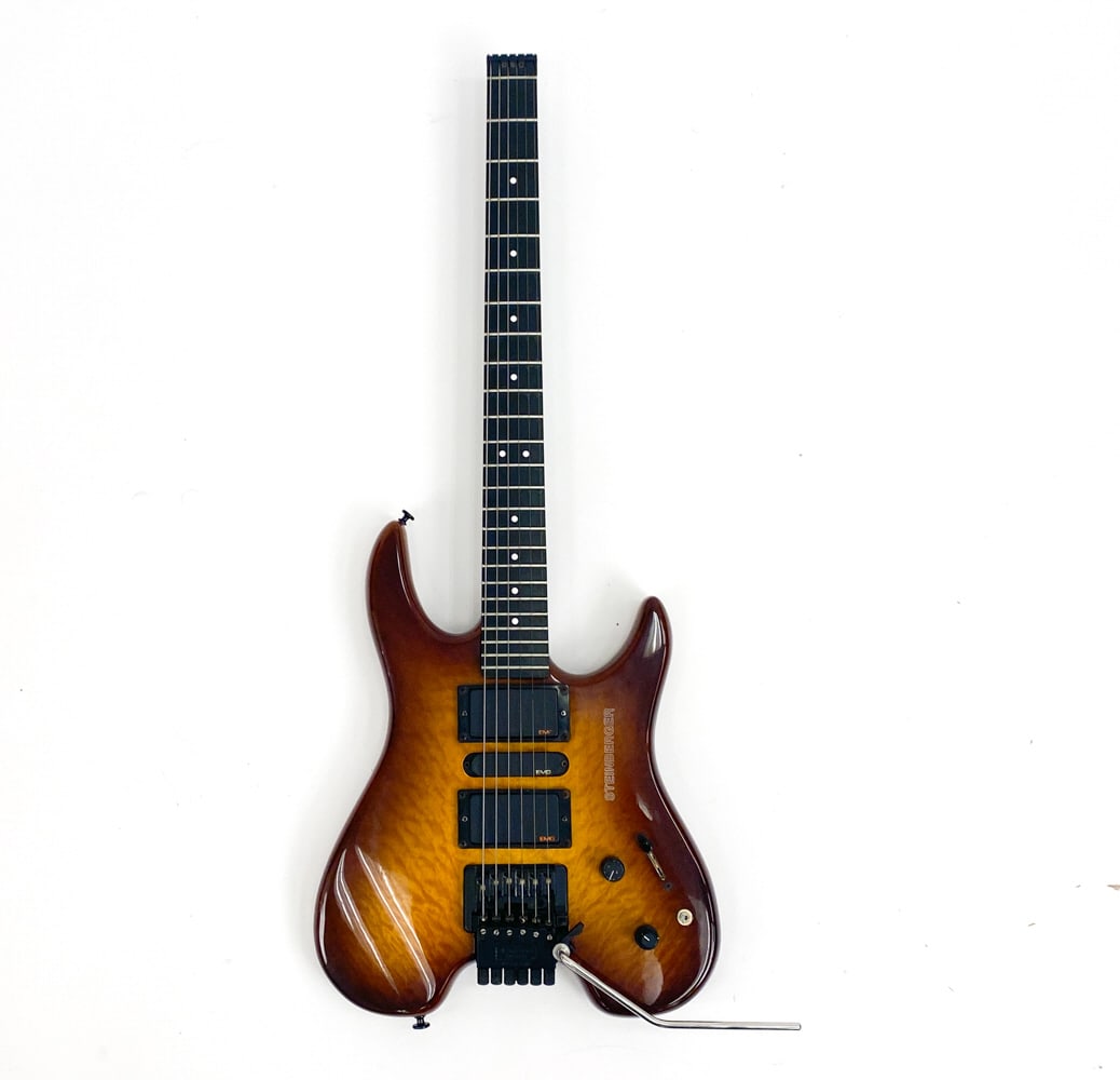 STEINBERGER GM3TA HONEY BURST HEADLESS GUITAR: #TN16301, c. 1990-1995. Sunburst quilted top finish with black hardware and white dot inlays on fretboard. EMG pickups. Condition: Slight scuffs and scratches on body, and the pickups do not appear to