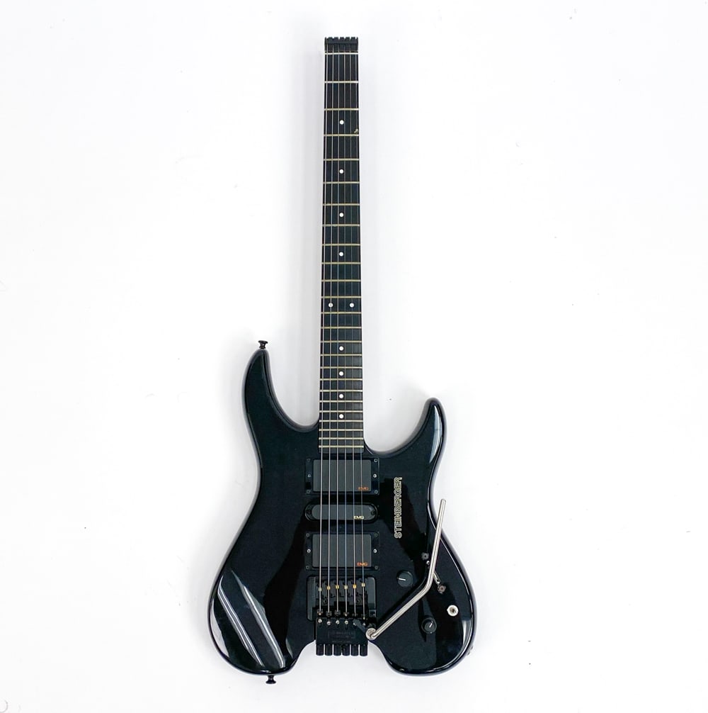 STEINBERGER BLACK HEADLESS ELECTRIC GUITAR: #N000742, c. 1990. Black gloss finish with all-black hardware. EMG pickups. Richlite fingerboard with white dot inlays. Condition: Some scuffs and wear marks on body and backplate. Pickups are not wor