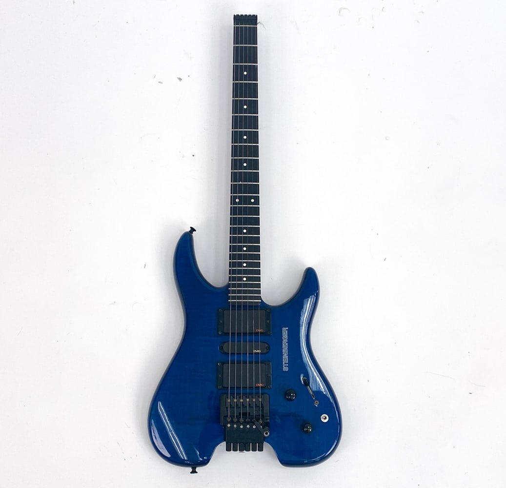 STEINBERGER GM3T HEADLESS ELECTRIC GUITAR: #N001078, c. late 1980s. Deep blue gloss tiger stripe finish with black hardware. White dot inlay markers on fingerboard. Condition: Some scuffs and scratches including a couple small chips on the bod