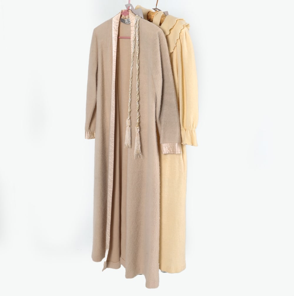 DANIELE DE BLANZY HOUSE COATS: Daniele de Blanzy house coats in wool, fleece, and satin (cream tone). Dimensions: Both Approx L 55" x Waist W 20" x Sleeve L 22.5". Condition: Some wear to fabric, slight pilling. Wear consistent wit