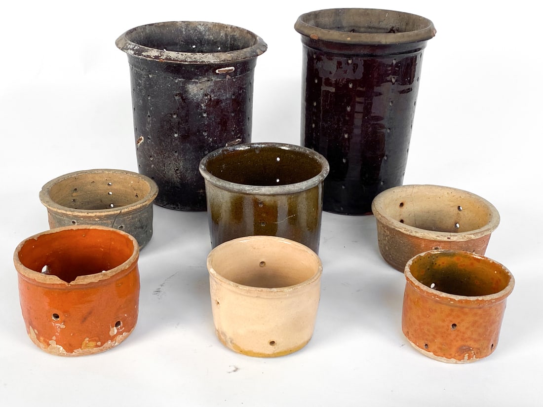 FRENCH POTTERY CHEESE STRAINER GROUPING: Eight pottery cheese/ butter strainers of varying sizes. Dimensions (largest) H 9.25" x Dia 7" Condition: Moderate nicks and scuffs throughout all strainers. Cracks and marks to pottery and terracotta