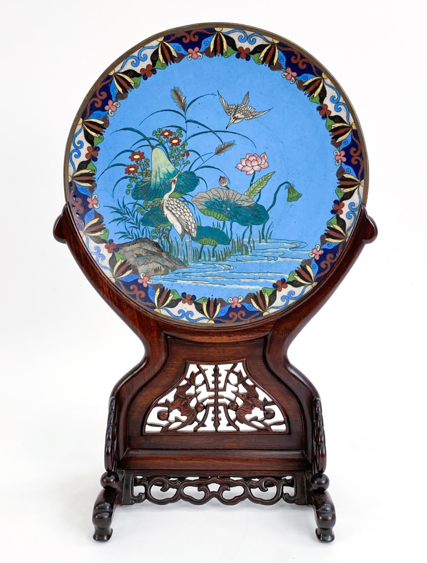 JAPANESE MEIJI CLOISONNE ENAMEL CHARGER: Hand painted scene on plate with carved wooden base. Apparently unsigned. Dimensions: (On stand) H 19" x W 12.5" x D 6.5" Condition: Few marks to plate and base.