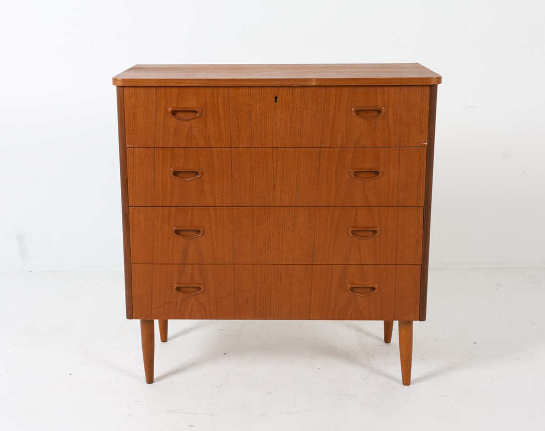 SWEDISH TEAK CHEST OF DRAWERS C. 1960S: With molded inset drawer pulls. With elegantly tapered legs. Dimensions: H 33" x W 32.5" x D 16.5". Condition: No key included. Few filled gouges to back corner, as shown in photos. Scuffs to drawer f