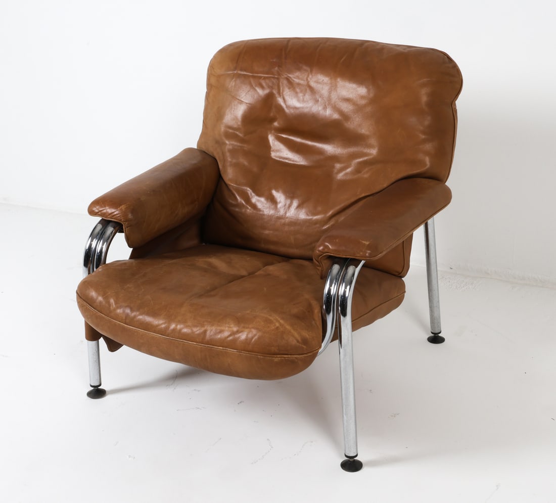 EICHENBERGER FOR DE SEDE "KANGAROO" LOUNGE CHAIR: Designed by Hans Eichenberger for De Sede. Cognac leather and chrome steel frame. Magazine holder hangs from proper right armrest. Switzerland, circa 1970s. Dimensions: H 31.5" x W 33" x D 30", SH 14.