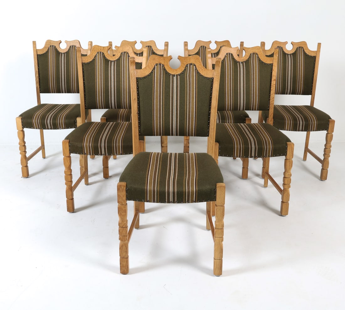 (7) KJAERNULF STYLE DANISH OAK DINING CHAIRS: Brutalist carved oak. Wool upholstery with nail head trim. Dimensions: H 37.25" x W 18.5" x D 17.5", SH 18" Condition: Upholstery has minor blemishes. Oak frames have scattered marks and scuffs. Wear 