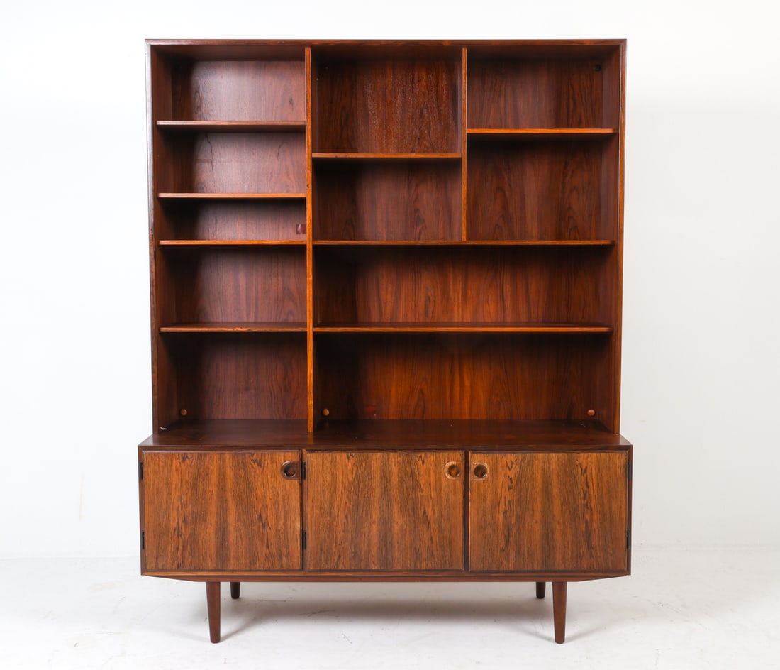 SVEN ELLEKAER ROSEWOOD BOOKCASE CABINET C. 1960S: Danish label to back corner. Adjustable shelves. Molded cabinet handles. Dimensions: H 73" x W 58.75" x D 20" Condition: Scattered scratches to surfaces. Cabinet has slight musty odor. Previous repair