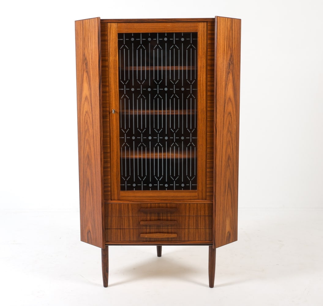DANISH ROSEWOOD CORNER CABINET C. 1960S: Key included. Glass panel with frosted decoration. Dimensions: H 57" x W 34.5" x D 22". Condition: Few light scuffs and scratches, scuff to area near latch. Wear consistent with age and use. DMO025