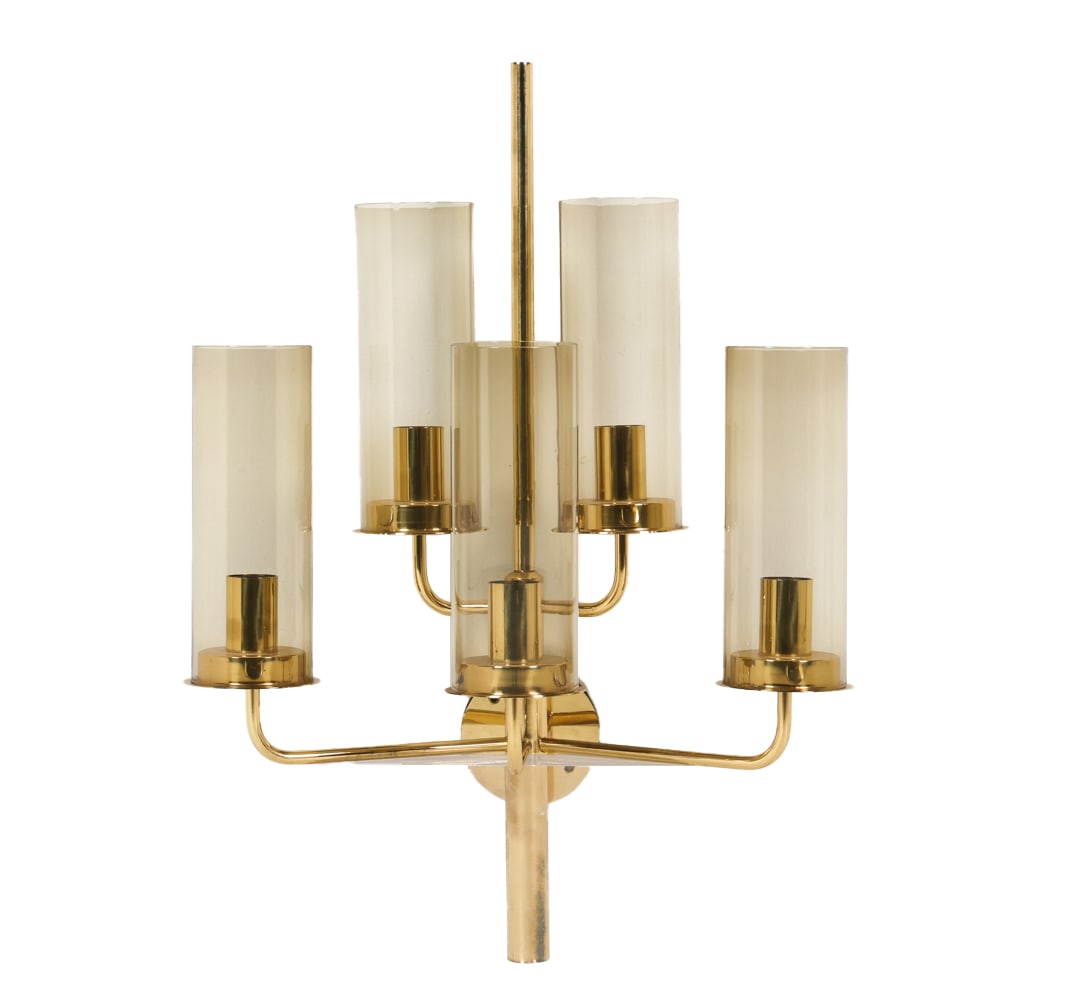 HANS AGNE JAKOBSSON SWEDISH BRASS SCONCE C. 1960S: Brass wall sconce with smoke glass cylindrical shades. Dimensions: H 24.5" x W 18" x D 11". Condition: Wiring untested. Few scuffs and surface scratches. Wear consistent with age and use.