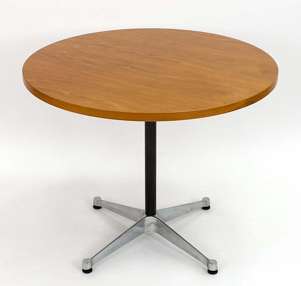 EAMES HERMAN MILLER ROUND TABLE: Originally designed by Charles & Ray Eames in 1964. Walnut top, steel column, aluminum base. Circa 2000. Tag on underside. Dimensions: H 29" x Dia 35.75" Condition: Very minor surface marks to top.