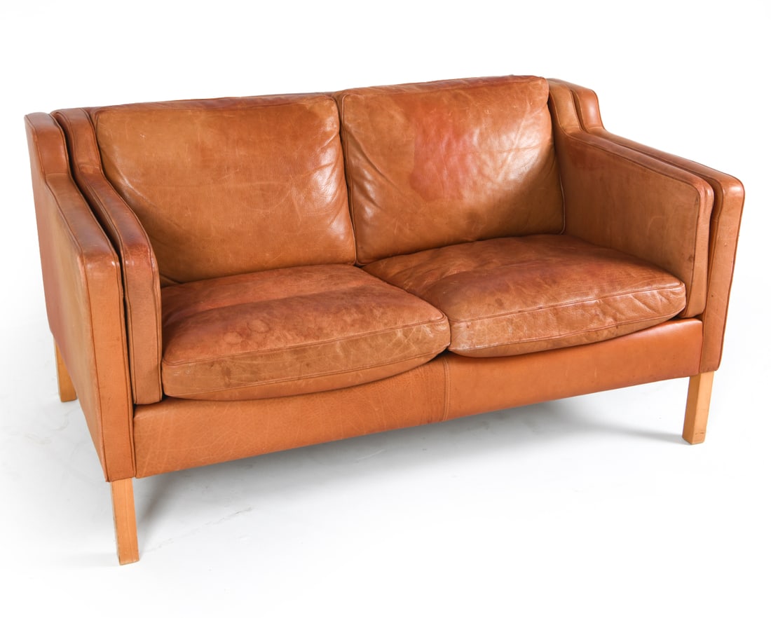 STOUBY DANISH BEECH & LEATHER LOVESEAT SOFA C.1970: Cognac-tone leather. Dimensions: H 28.75" x W 55.75" x D 32", SH 17" Condition: Moderate discoloration and blemishes to cushions and upholstery. Tears to seat back edges. Wear consistent with age and