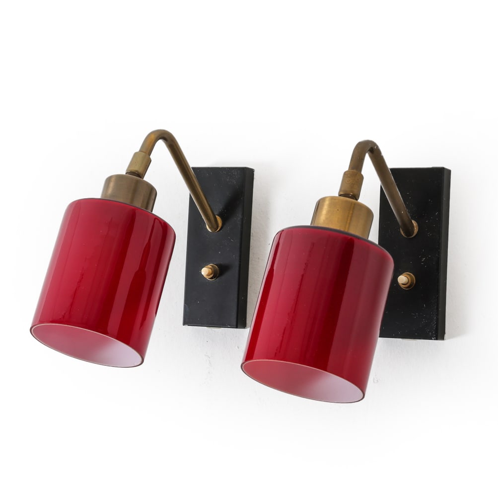 ATTR. JO HAMMERBORG GLASS WALL SCONCES: Red cylindrical glass shades with brass stems. Denmark, circa 1970s. Dimensions: H 8" x W 3.5" x D 7.5". Condition: Wiring untested. Few white paint marks. Wear consistent with age and use.