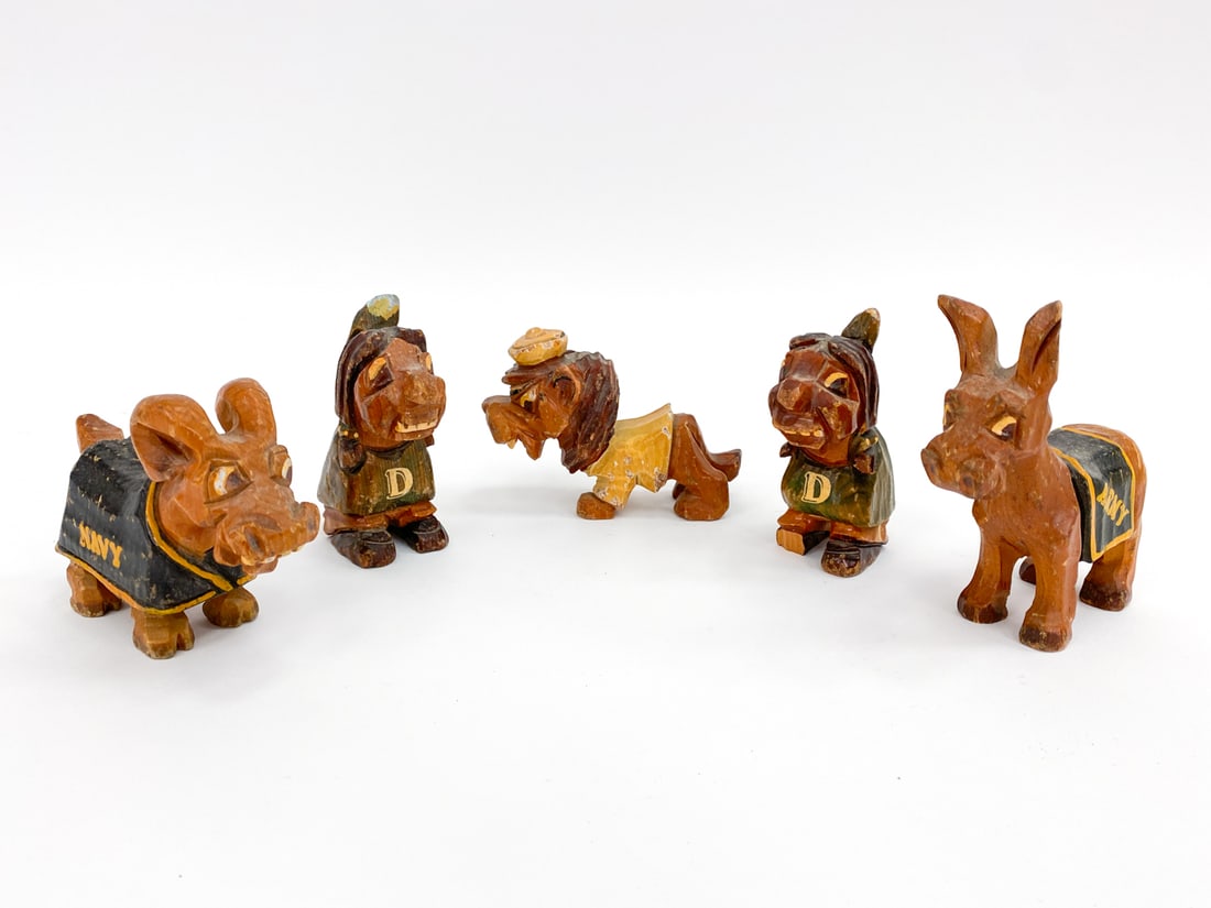 CARTER HOFFMAN HAND-CARVED WOODEN SCULPTURES: Includes a Columbia University lion, (2) Dartmouth Indian mascots, Navy goat mascot, and an Army mule mascot. Circa 1950s. Signed on undersides. Dimensions: H 4.75" x W 1.75" x D 2.5" Condition: Wear