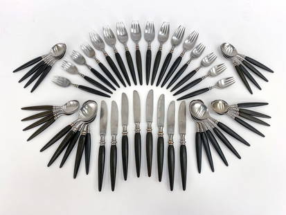 GUILDCRAFT MID-CENTURY STAINLESS FLATWARE GROUPING: Handles are a black composite material with stainless steel ends. All marked. Made in Japan. Includes (26) spoons, (16) forks, and (8) butter knives. Condition: Some handling wear, wear consistent