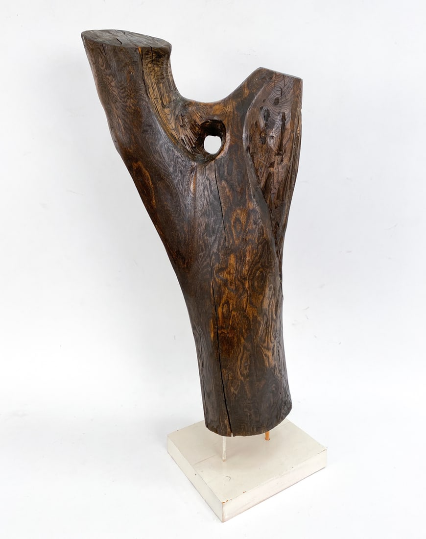 CARVED WOOD SCULPTURE: Solid wood that has been carved and put onto a stand. Apparently unsigned. Dimensions: H 32" x W 13" x D 10" Condition: One of the dowels holding the trunk on the base is split. Naturally forming spli