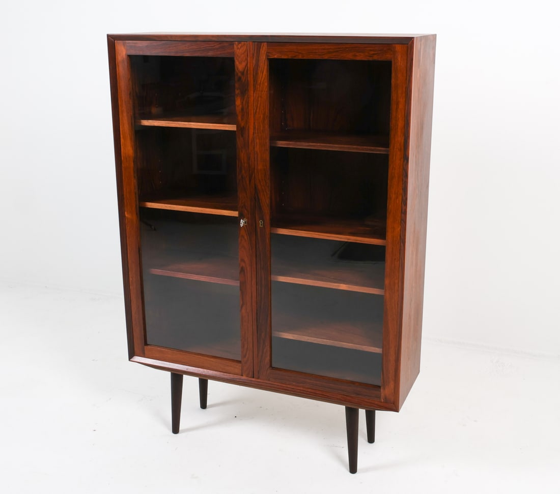 OMANN JUN STYLE ROSEWOOD BOOKCASE CABINET: Includes (1) Key. Glass cabinet doors with adjustable shelves. Denmark, circa 1970s Dimensions: H 56" x W 39.5" x D 12" Condition: Slight dings to exterior edges. Presents well overall.