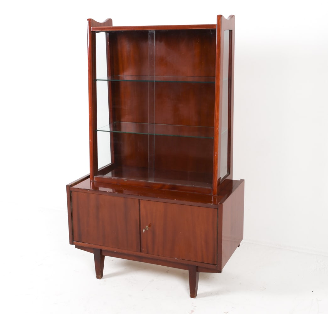 RAJMUND HALAS FOR JAROCINSKA POLISH WALNUT CABINET: Model 1019. Labeled to backside. 2 pieces. Glass cabinet connects to base with wooden dowels. Circa 1960s.Dimensions: H 57" x W 35.5" x D 17"Condition: Scattered dings and blemishes to cabinet.