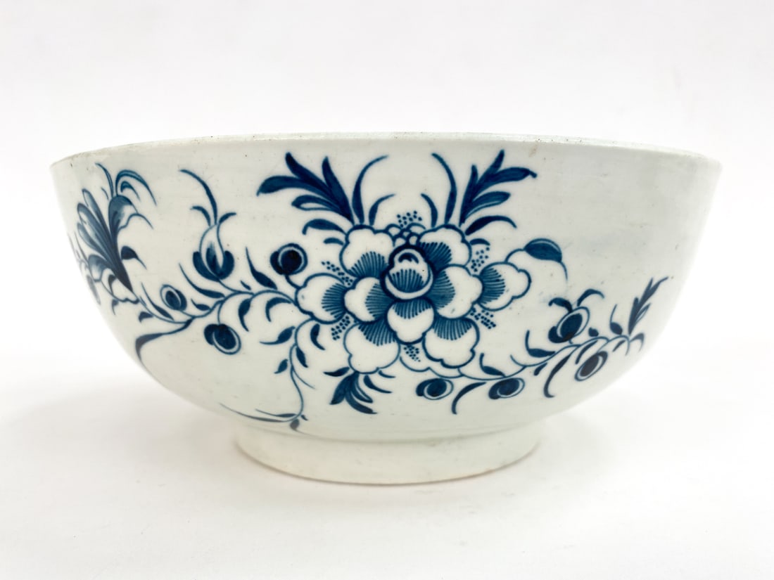 ANTIQUE BLUE AND WHITE PORCELAIN BOWL: Appears to be Worcester from the late 18th c. White ground with blue painted floral details. Apparently unsigned, with dealer label on underside. Dimensions: H 3.5" x Dia 8.25" Condition: Light scratc