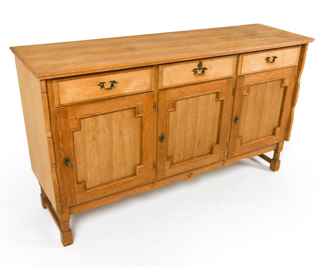 HENNING KJAERNULF STYLE DANISH OAK SIDEBOARD: Key included. Brass hardware. Adjustable shelves. Carved decoration to lower apron. Denmark, circa 1970s. Dimensions: H 34.5" x W 59" x D 17". Condition: Some faint discoloration to top, few water rin