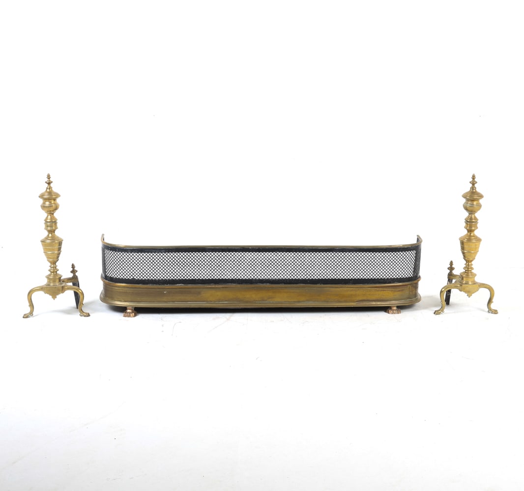 BRASS FIREPLACE FENDER & ANDIRONS: 1 fender and a pair of andirons. Dimensions: (Andirons) H 23.5" x W 11" x D 9.5" Fender W 54" Condition: Tarnishing to brass. Oxidation to fender. Slight scuffs and marks, consistent with age and use.