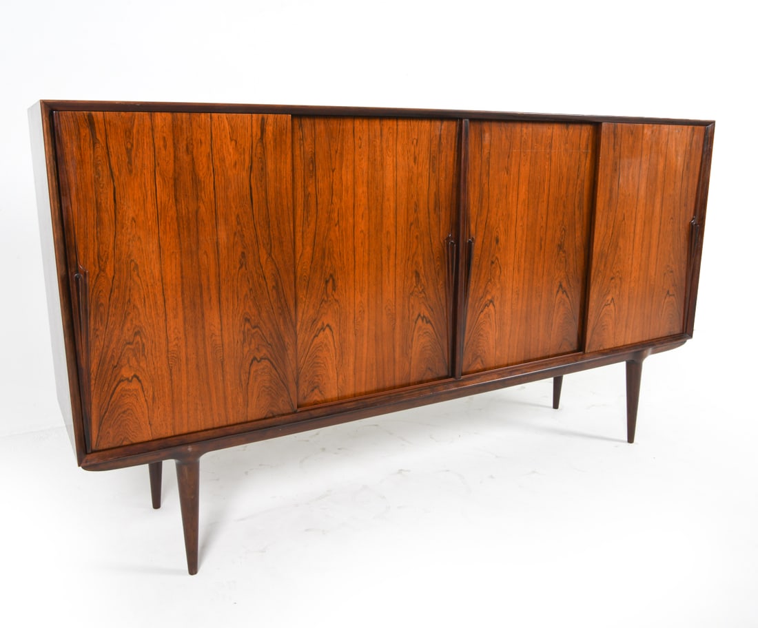 OMANN JUN MODEL 19 ROSEWOOD SIDEBOARD C. 1960S: Tag inside cabinet. Adjustable shelves. Sits freely on base. Dimensions: H 43.5" x W 70" x D 18". Condition: Few scuffs and surface scratches, faint water rings. Wear consistent with age and use. JBN