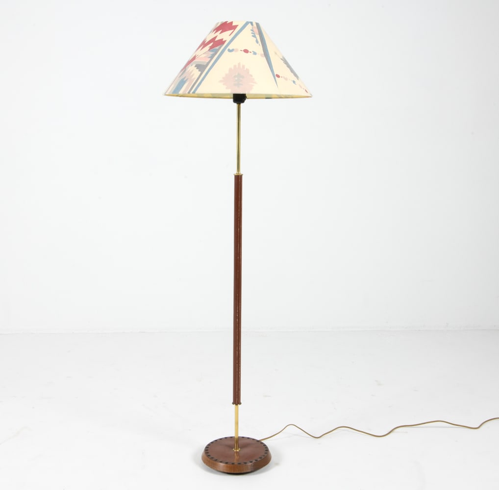 MID-CENTURY DANISH TEAK & LEATHER FLOOR LAMP: Circa 1960s. Woven leather to center post and to base with tack edges. Dimensions: (With shade) H 55" x Dia 17.5" Condition: Scuffs and light blemishes to leather. Tarnishing to brass posts. Slight so
