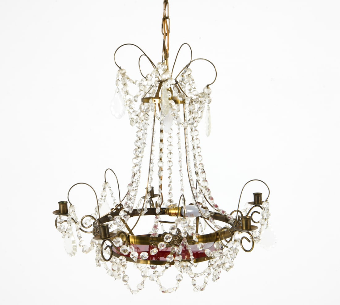 HAGA STYLE BRASS & GLASS CHANDELIER C. 1960S: Brass chandelier with crystal drops and red glass disc at bottom. Light in center, candle holders around rim. Sweden, circa 1960s. Dimensions: H 22.5" x Dia. 24". Condition: Wiring untested. Minor scu