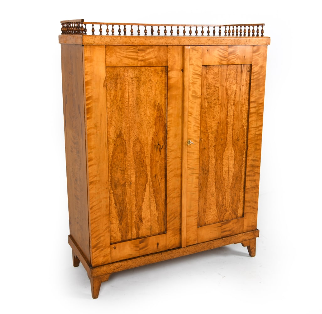 ART DECO SCANDINAVIAN BIRCH CABINET C. 1930S: Key included. Birch wood cabinet with banister trim on top. Bone inlay around key hole. Removable shelves. Dimensions: H 56" x W 42" x D 17.5". Condition: Minor scuffs and dings, some stress splits al