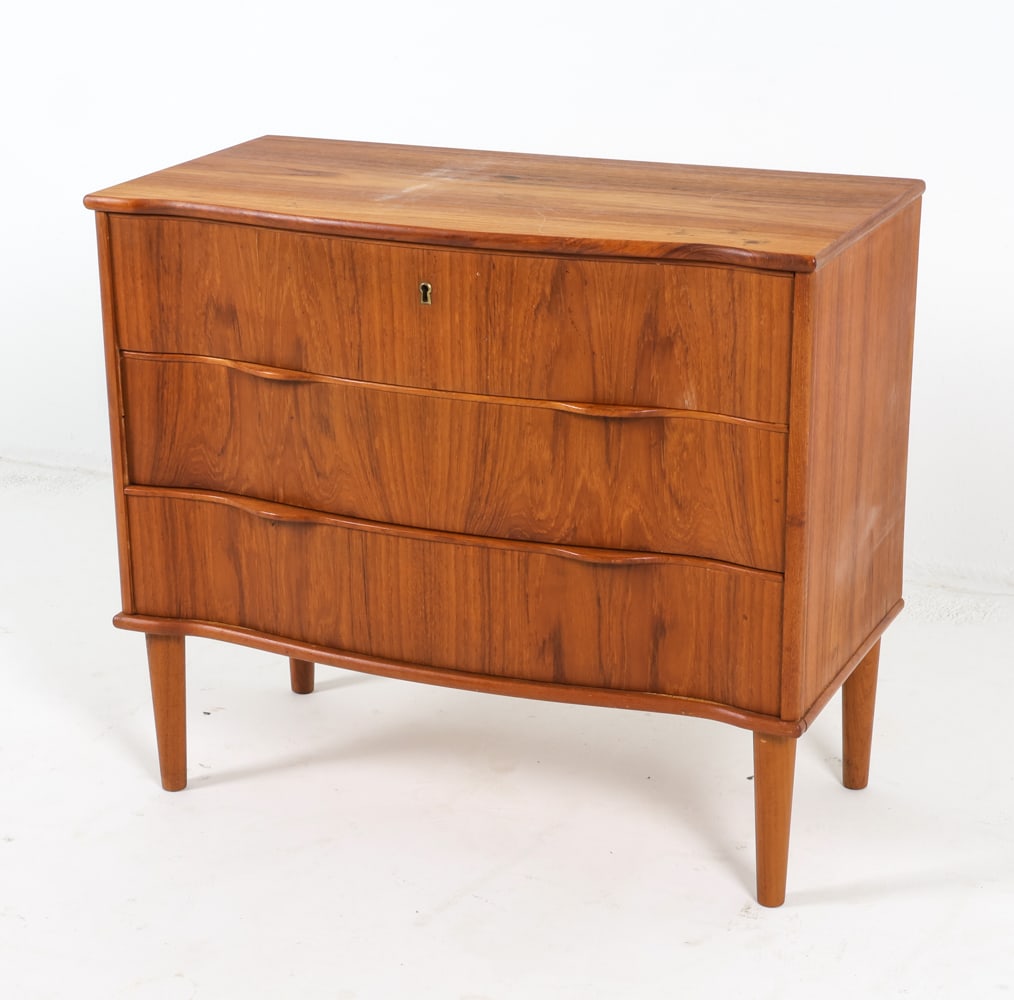 DANISH TEAK CHEST OF DRAWERS C. 1960S: Key included. Serpentine front. Dimensions: H 26.5" x W 30.75" x D 15.5". Condition: Some sun fading and discolored spots to top. Scuffs and scratches. Wear consistent with age and use. GCE 193