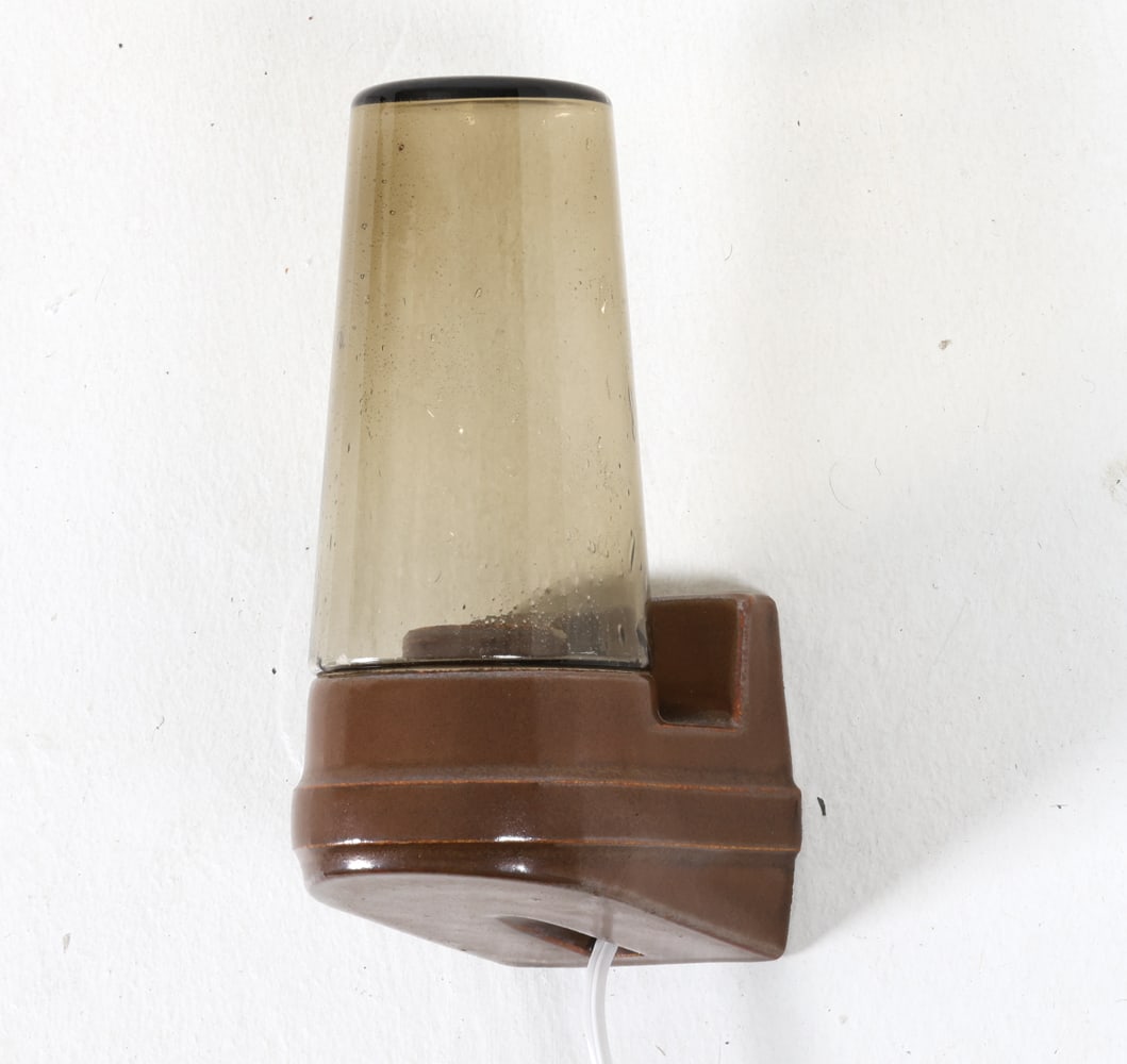 SIGVARD BERNADOTTE IFO CERAMIC & GLASS SCONCE: Ceramic base with glass conical shade. Sweden, circa 1960s. Dimensions: H 7.5" x W 3" x D 4". Condition: Wiring untested, cord cut. Minor scuffs. Wear consistent with age and use.