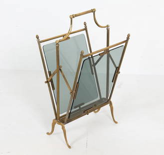 MAISON BAGUES STYLE BRASS & GLASS MAGAZINE RACK: Brass frame with inset glass panels. Dimensions: H 23.5" x W 13' x D 11" Condition: Moderate tarnishing to brass frame. Loss to exterior hardware on one side. Wear consistent with age and use.