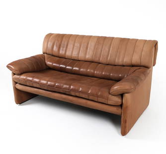 DE SEDE DS 86 LEATHER SOFA C. 1970S: Marked De Sede to underside of cushions. Brown-tone leather upholstery. Dimensions; H 31" x W 60" x D 32", SH 16" Condition: Moderate blemishes throughout. Creases and discoloration to leather. Wear c