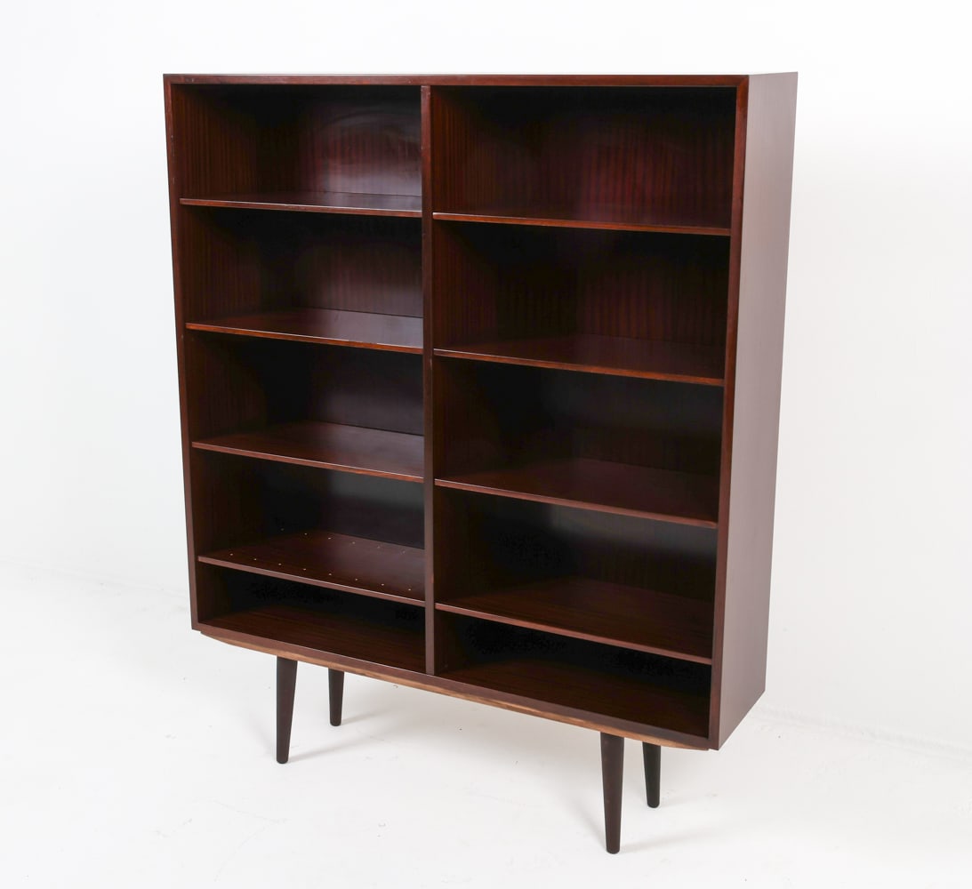 OMANN JUN MODEL 6 MAHOGANY BOOKCASE C. 1960S: Label to backside. Adjustable shelves. Denmark. Circa 1960s. Dimensions: H 58.25" x W 47.5" x D 11.25" Condition: Filled holes to backside. Possibly missing divider shelves. Minor dings to shelves. Pr