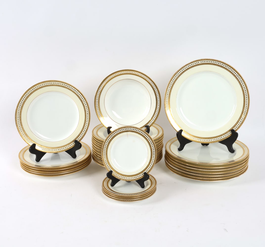 MINTON CHINA GILT RIM PORCELAIN GROUPING: Cream and gilded decoration. Includes (31) pieces. Marked on backsides. Dimensions: Dinner Plates Dia. 10.25". Saucers Dia. 6". Condition: Few hair lines, chips, and rubbing to gilt. Wear consistent w