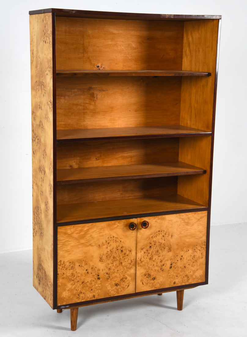 MID-CENTURY POLISH BURL BOOKCASE CABINET: Circa 1960s. High-gloss burl maple veneer with rounded acrylic cabinet pulls. Outer edges in a contrasting trim. Dimensions: H 65.5" x W 37.5" x D14" Condition: Minor discoloration and blemishes to sh
