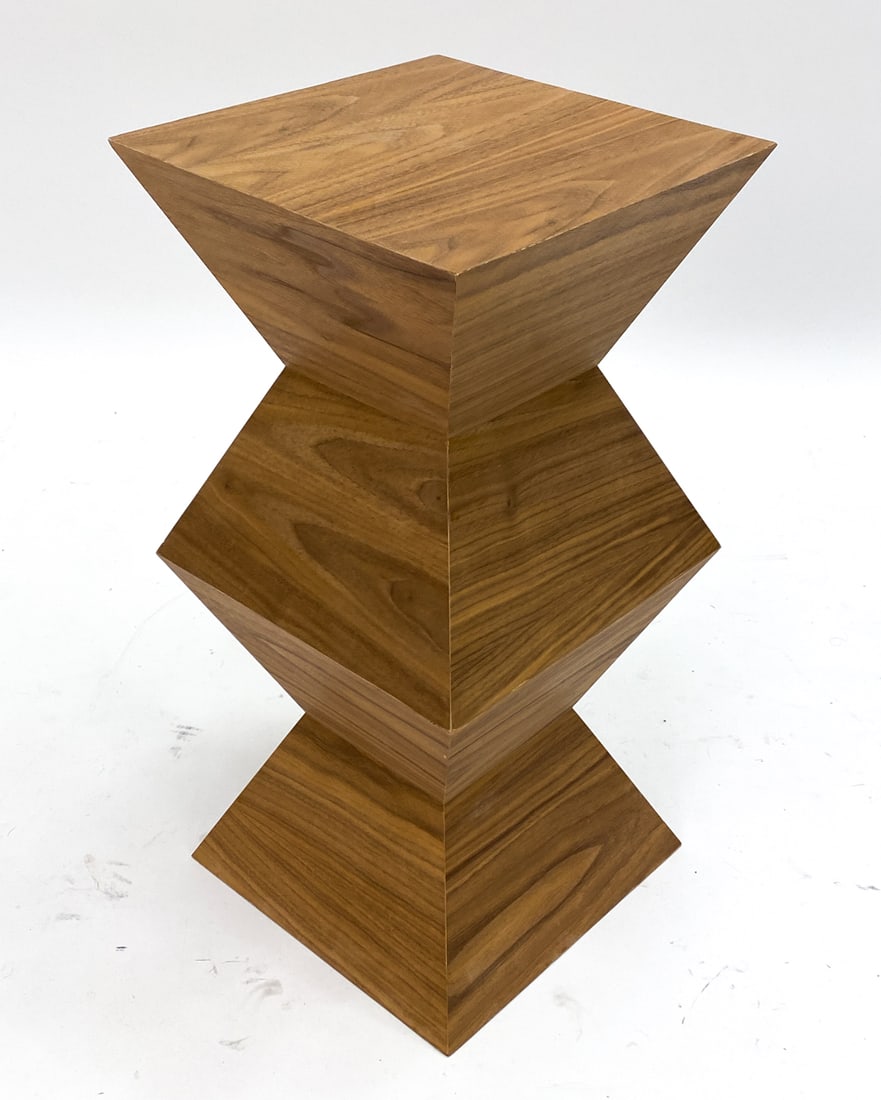 CONTEMPORARY WOODEN PEDESTAL STAND: Modern wood veneer pedestal stand with a distinctive geometric design. Dimensions: H 2' x L 11 3/4" x D 11 3/4" Condition: Some chipping and wood loss to the edges in various spots.