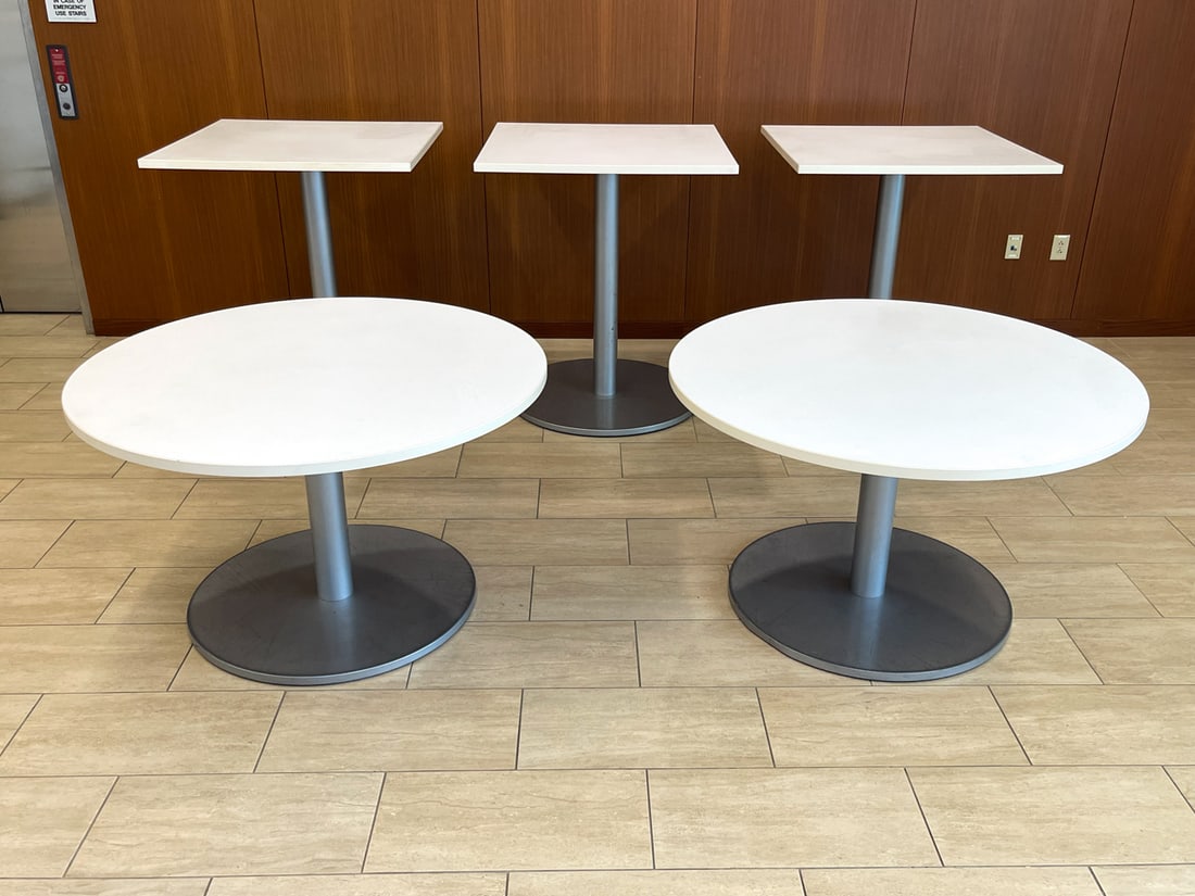 GROUPING OF PEDESTAL TABLES: Includes (3) smaller square high top tables, (2) larger round tables each with stainless steel bases, also includes hardware to put tables together, currently separated from bases. Dimensions: (Larges