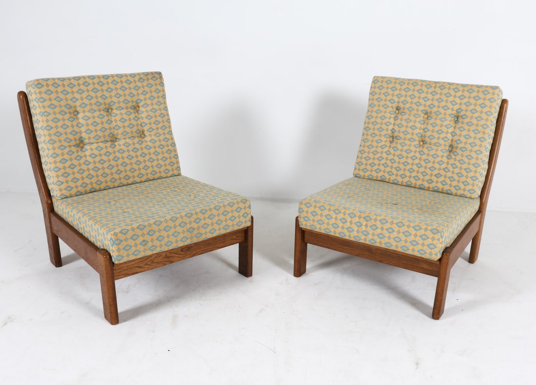 PAIR OF DANISH OAK LOUNGE CHAIRS 1970S: Brutalist oak lounge chairs in the style of Carl Straub. Denmark, circa 1970s. Dimensions: H 30.5" x W 26" x D 28" x SH 15.5". Condition: Minor scuffs to frame. Slight sun fading to cushions. Wear con