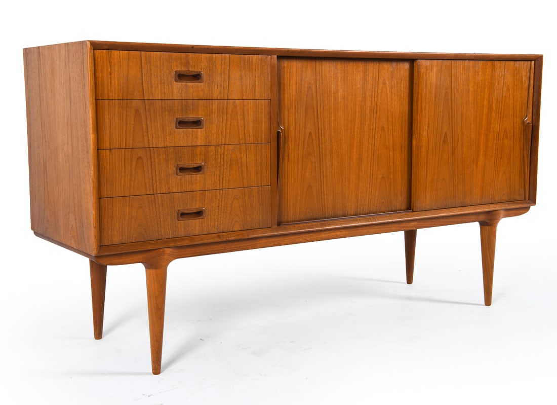 OMANN JUN DANISH TEAK SIDEBOARD C. 1960S: Constructed from teak, Apparently unmarked. Dimensions: H 33" x W 63" x D 19" Condition: Sun fading to the surface. Moderate blemishes and scuffs to the interior shelves. Slight musty odor to the inte
