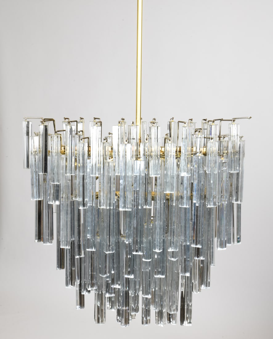 PAOLO VENINI TRIEDRI STYLE WATERFALL CHANDELIER: Paolo Venini triedri style brass and crystal chandelier. Brass fixture with many prism drop crystals of varying sizes. Circa 1960s. Dimensions: H 72" x W 29" x D 16" Condition: Chips and small cracks