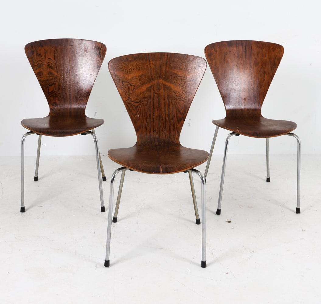(3) ARNE JACOBSEN STYLE ROSEWOOD DINING CHAIRS: Rosewood veneer on molded plywood seats, chrome steel legs. Dimensions: H 33" x W 18" x D 21", SH 17.5" Condition: Showing signs of wear including some scratches, losses and chips to veneer. Oxidation