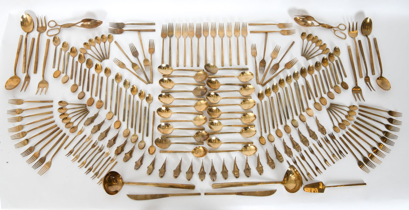 EXTENSIVE GOLD-TONE FLATWARE SERVICE: Large grouping of flatware, marked nickel-plated. Including rare whale form knife rests. Dimensions: H 9" x W 2" Condition: Wear consistent with use and age.
