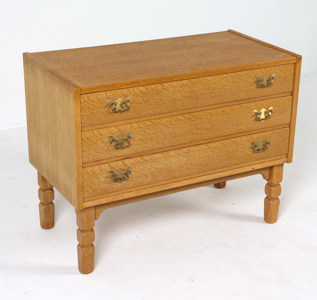 HENNING KJAERNULF STYLE OAK CHEST 1970S: Oak chest with turned legs and brass drawer pulls. Denmark, circa 1970s. Dimensions: H 25.25" x W 33" x D 17". Conditions: Light surface wear consistent with age and use, a few areas of minor discolor