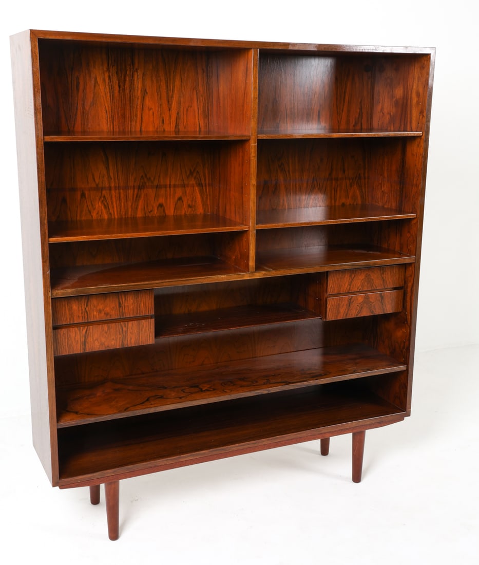OMANN JUN DANISH ROSEWOOD BOOKCASE C. 1960S: Adjustable shelves. Small drawers to lower center shelf. Denmark, circa 1960s. Dimensions: H 55.5" x W 47.25" x D 11.5". Conditions: Light surface wear consistent with age and use, good presentation o
