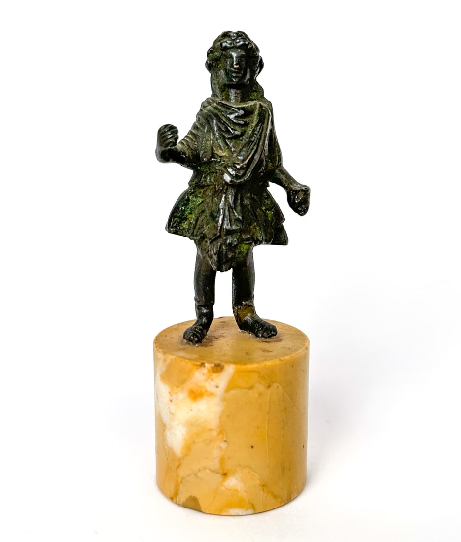 ROMAN 2ND/3RD C. BRONZE LAR FIGURE: Vigorously sculpted bronze with good patina, on marble base. Dimensions: (Figure) H 4" x W 2" x D 1.5" (On stand) 6" Condition: Appears to have a repaired break to one ankle. Few chips to stand. Ancie