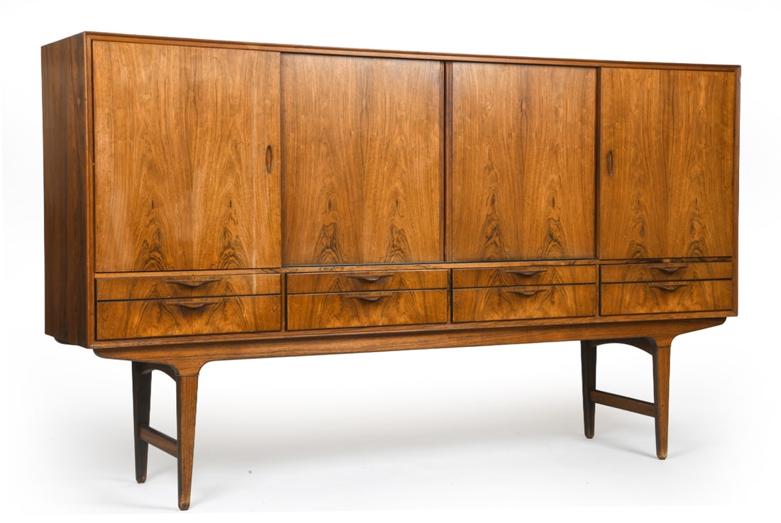 ATTR. GUNNI OMANN FOR OMANN JUN ROSEWOOD HIGHBOARD: Tall rosewood cabinet/highboard with prominent grain pattern, sculpted handles and sliding doors. Apparently unmarked. Denmark, circa 1960s. Dimensions: H 46.5" x W 80" x D 16.75" Condition: Some soil