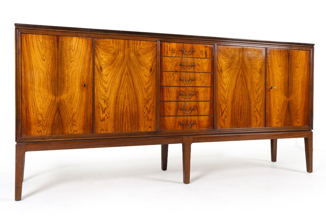 HUNDEVAD STYLE DANISH ROSEWOOD SIDEBOARD C. 1960S: Rosewood veneer sideboard in the style of Poul Hundevad. Key included. Adjustable shelves. Felt lined drawers. Brass drawer pulls. Scandinavian, circa 1960s. Dimensions: H 39.5" x W 83.5" x D 20". Con