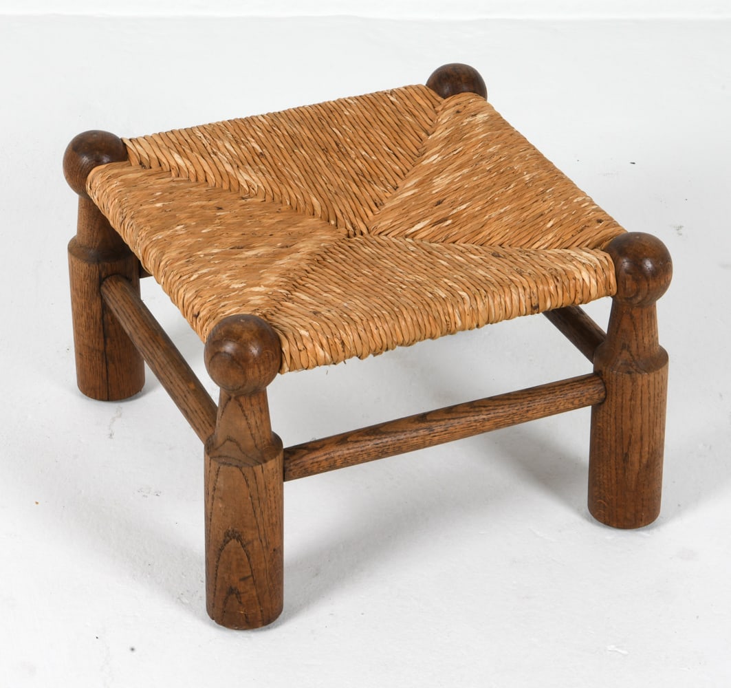STYLE OF DUDOUYT FRENCH OAK & RUSH STOOL C. 1940S: Oak and rush seat footstool in the style of Charles Dudouyt. France, circa 1940s. Dimensions: H 11.75" x W 17.5" x D 17.5" Condition: Wear consistent with age and use. PP151