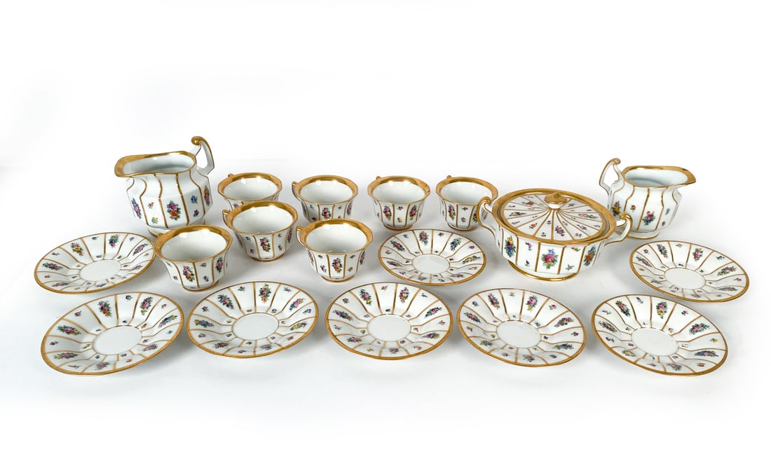 ROYAL COPENHAGEN HENRIETTE PORCELAIN GROUPING: Grouping with flowers and golden rim pattern. Marked to undersides. Includes: two creamers, one sugar bowl, eight saucers, seven teacups. Dimensions: (Creamer) H 4" x W 5" (Saucers) Dia 5" Condition: