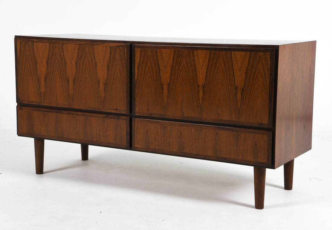 GUNNI OMANN ROSEWOOD CREDENZA SIDEBOARD C. 1960S: For Omann Jun. Small credenza sideboard with (4) drawers. Holes in back for wires. Denmark, circa 1960s. Dimensions: H 24.5" x W 47.25" x D 17.5". Condition: Thin surface scratches. Wear consistent wi