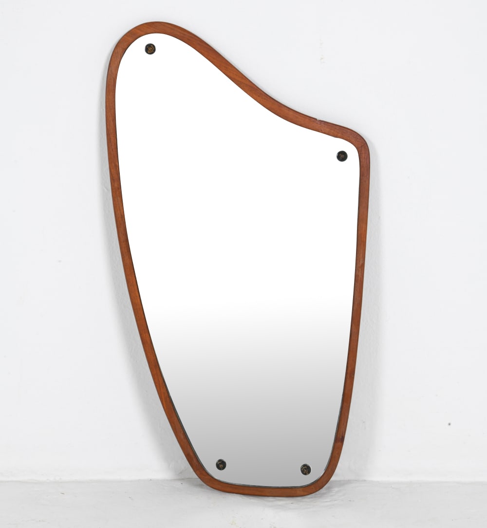 DANISH TEAK ASYMMETRICAL WALL MIRROR C. 1960S: Teak wall mirror with beveled glass in organic shape. Denmark, circa 1960s. Dimensions: H 30.5" x W 17.25". Condition: Minor scuffs, rubs to wooden screw caps. Wear consistent with age and use. CLEV09